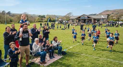 Families cheering from the sideline at a Coast Rugby Academy game day