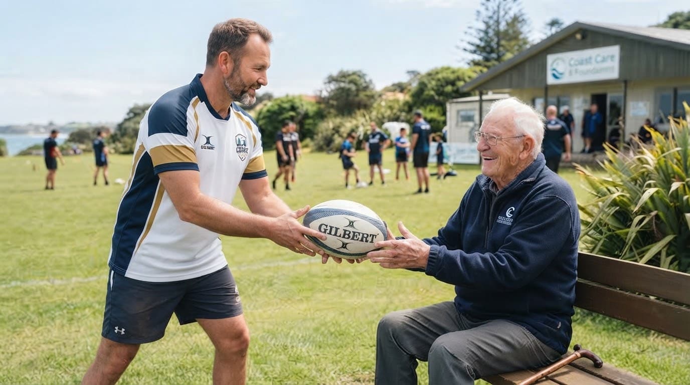 A Coast Care Rugby coach handing a rugby ball to a seated resident outdoors