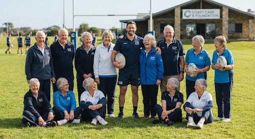 Group photo of Coast Care Rugby participants and a coach on the field